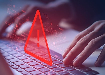 Hands at a keyboard with a large red triangle and exclamation point above it