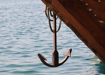 A ship anchor hanging above the water
