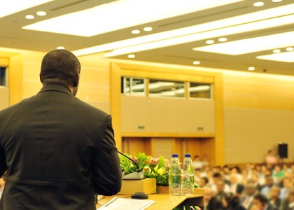 A man speaking at a podium to a room full of people