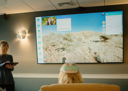 A room full of people watching a virtual reality simulation on a television monitor.