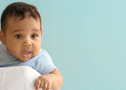 A doctor holds a baby over her shoulder.