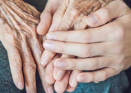 Two elderly hands being held by a younger hand.