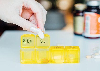A hand organizing medicine into a pill organizer.