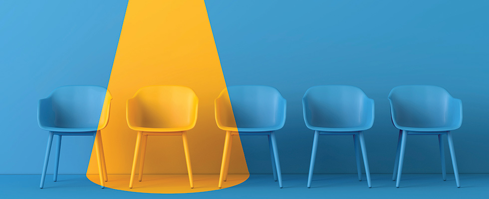 An image of a row of chairs. All are blue against a blue background except one that is yellow against a yellow background